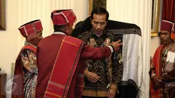 Pemangku Hutan Adat dari Tombak Haminjon (Kemenyan) Provinsi Sumatera Utara saat akan mengalungkan kain ulos kepada Presiden Joko Widodo (Jokowi) usai pencanangan pengakuan Hutan Adat di Istana Negara, Jakarta, Jumat (30/12). (Liputan6.com/Faizal Fanani)