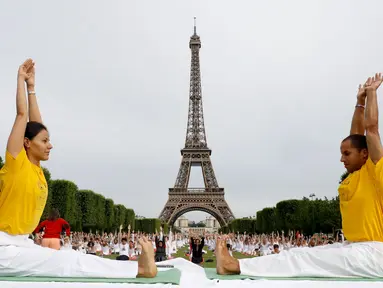 Para peserta ambil bagian dalam acara yoga massal untuk memperingati Hari Yoga Internasional yang jatuh pada 21 Juni di Champs de Mars, depan menara Eiffel, Paris, Prancis, Minggu (17/6). (AFP PHOTO/FRANCOIS GUILLOT)