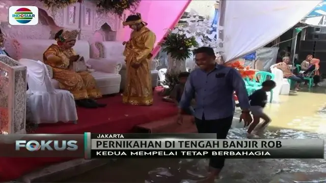 Pasangan pengantin di Penjaringan, Jakarta Utara ini tetap melangsungkan pernikahan meski area resepsi mereka tergenang banjir rob.
