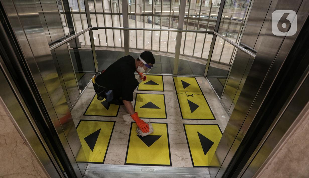 Petugas membersihkan lift yang dipasangi garis batas setiap pengguna di Senayan City, Jakarta, Selasa (9/6/2020). Senayan City siap menyambut pengunjung kembali pada 15 Juni 2020 dengan menyediakan sensor tanpa sentuh untuk lift hingga hand sanitizer di beberapa titik. (Liputan6.com/Johan Tallo)