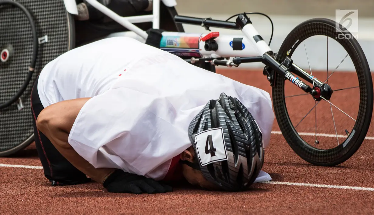 Pebalap kursi roda Indonesia, Jaenal Aripin, melakukan sujud syukur saat berselebrasi usai meraih medali perak pada Asian Para Games cabang atletik nomor balap kursi roda 200 meter T 54 di SUGBK, Jakarta, Jumat (12/10). (Bola.com/Vitalis Yogi Trisna)