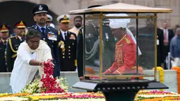 Presiden India, Droupadi Murmu menebarkan kelopak bunga mawar di tugu peringatan Mahatma Gandhi di Rajghat pada hari ulang tahun kematian Gandhi di New Delhi, India, Senin (30/1/2023). Gandhi meninggal dunia di usia 78 tahun, peringatan kematian Gandhi, yang secara luas dikenal di India dan diperingati sebagai Hari Martir. (Sajjad HUSSAIN/AFP)