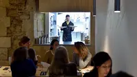 Asisten memasak dengan down syndrome memegang piring berisi menu makanan di restoran "Le Reflet" di Nantes, Prancis Barat, 9 Februari 2017. Lelievre (26), mempekerjakan sejumlah karyawan yang memiliki down syndrome di restorannya. (LOIC VENANCE/AFP)