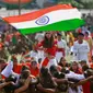 Seorang gadis mengibarkan bendera India saat para siswa melakukan tarian selama perayaan Hari Kemerdekaan India, di Jammu, India, (15/8). India merdeka dari kolonialis Inggris pada tahun 1947. (AP Photo / Channi Anand)