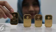 Petugas menunjukan emas batangan di kantor BNI Syariah, Jakarta, Senin (30/11). Harga jual-beli kembali (buyback) emas Antam turun Rp 1.000 usai akhir pekan kemarin naik di tengah turunnya harga emas global. (Liputan6.com/Angga Yuniar)