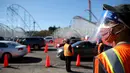 Relawan memandu pengendara di pusat vaksinasi COVID-19 drive-thru massal di tempat parkir Six Flags Magic Mountain di Valencia, California, Selasa (2/2/2021). Situs ini di salah satu dari lima situs vaksin corona utama yang dioperasikan oleh Los Angeles County. (VALERIE MACON/AFP)