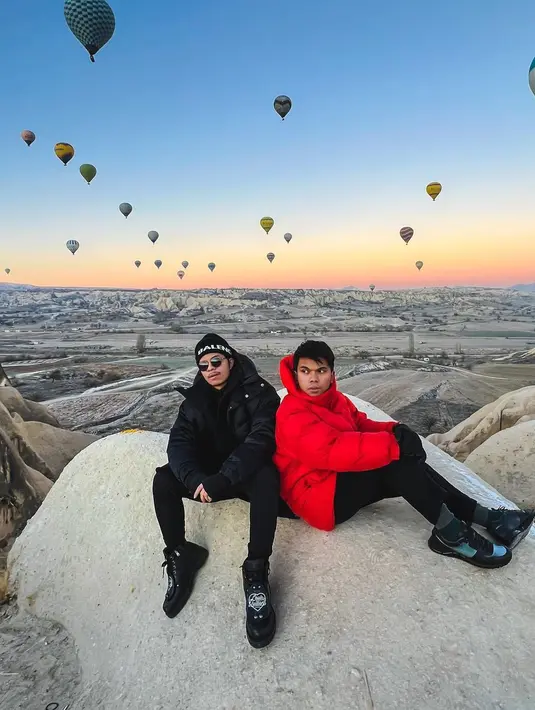 Terakhir adalah momen kebersamaan Atta dan Thariq yang berpose di sebuah batu dengan latar pemandangan balon-balon udara. Atta mengenakan outfit serba hitam, sedangkan Thariq terlihat mengenakan puffer jacket berwarna merah. Foto: Instagram.