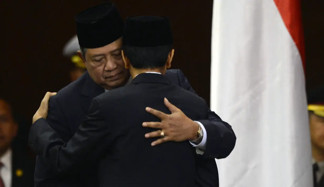 Presiden RI ke-6, Susilo Bambang Yudhoyono (SBY) merangkul presiden terpilih 2014, Joko Widodo (Jokowi) setelah upacara pengambilan sumpah di House of Representative di Jakarta pada 20 Oktober 2014. (AFP PHOTO / ROMEO GACAD)