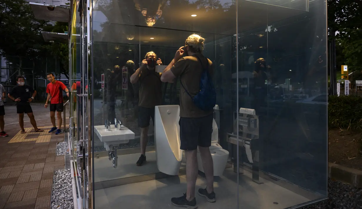 Seorang pria menggunakan toilet transparan di Haru-no-Ogawa Community Park di distrik Shibuya, Tokyo (19/8/2020). Toilet ini dirancang oleh Shigeru Ban dimana dinding luar kacanya akan berubah menjadi buram ketika kuncinya ditutup. (AFP Photo/Philip Fong)
