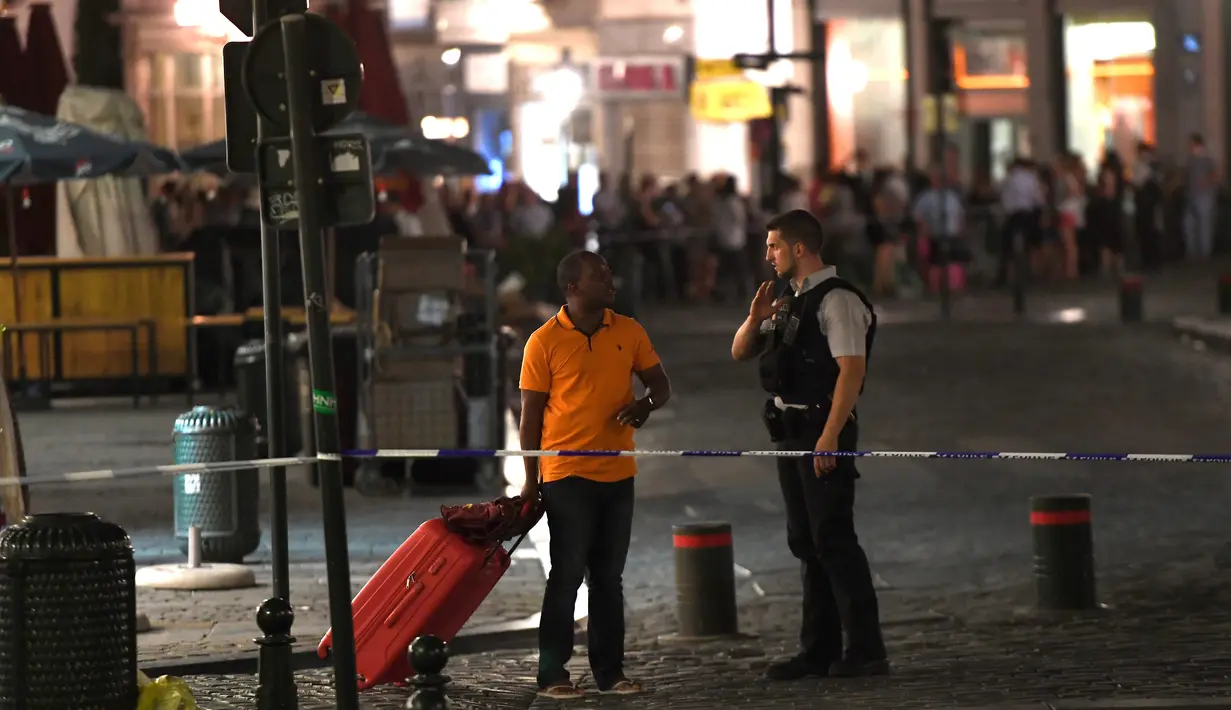 Polisi berbincang dengan salah satu calon penumpang usai terjadi ledakan di sebuah jalan di luar Gare Centrale di Brussels, Belgia (20/6). Dalam peristiwa ini tidak ada korban jiwa. (AFP Photo/Emmanuel Dunand)
