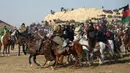 Penunggang kuda Afghanistan memperebutkan bangkai saat pertandingan olahraga tradisional Buzkashi di Mazar-i-Sharif, Afghanistan (20/12). Mereka merebutkan bangkai seekor binatang ternak yang dibawa di sekitar penanda atau bendera. (AFP/Farshad Usyan)