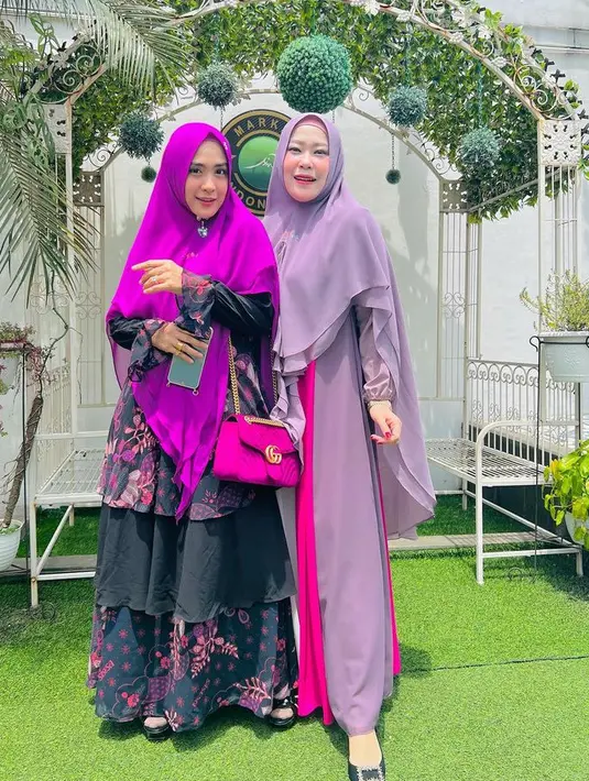 Ia juga tampil ceria dengan kerudung fuschia yang serasi dengan tas Gucci sling rantai. Dipadukan dress ruffle hitam bermotif bunga pink.  [@apriljasmine]