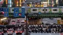 Pejalan kaki menyeberangi jalan raya saat kereta Yamanote Line melintas pada jam sibuk di Distrik Shinjuku, Tokyo, Jepang, Selasa (4/6/2019). Yamanote loop line menawarkan wisatawan untuk melihat kehidupan sehari-hari warga di pusat Kota Tokyo. (AP Photo/Jae C. Hong)