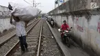 Sejumlah pengendara melintas di samping rel kereta yang berada di kawasan Banjir Kanal Barat, Jakarta, Selasa (20/3). Aksi nekat itu dilakukan dengan alasan demi mempersingkat waktu. (Liputan6.com/Arya Manggala)