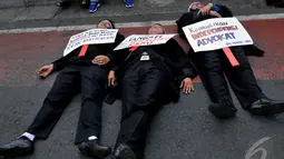 Tiga orang pengacara tidur telentang di jalan raya sebagai bentuk protes mereka kepada rencana pengesahan RUU Advokat oleh DPR, Jakarta, Kamis (11/9/2014) (Liputan6.com/Johan Tallo)