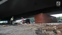 Petugas menutupi tumpahan oli dengan pasir pasca kecelakaan truk kontainer di kolong flyover Tomang, Jakarta, Kamis (28/6). Akibat peristiwa tersebut tumpahan oli tercecer sehingga sebagian jalan terpaksa ditutup sementara. (Merdeka.com/Iqbal S. Nugroho)