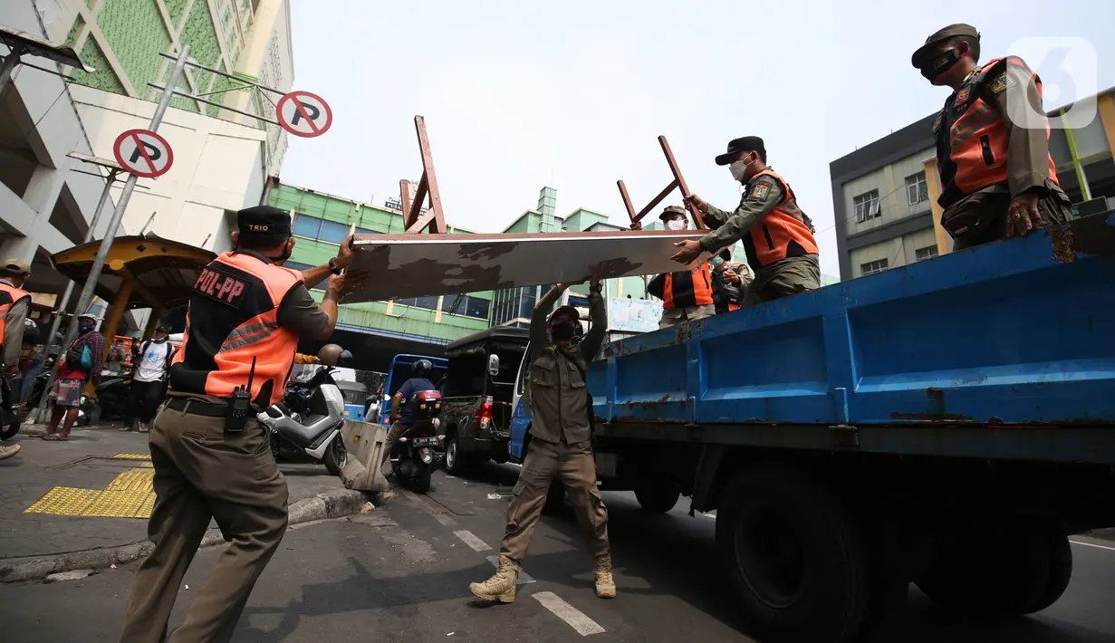 Petugas Satpol PP mengangkut meja pedagang kaki lima (PKL) yang bandel berjualan di trotoar Pasar Tanah Abang, Jakarta, Senin (4/10/2021). Penertiban dilakukan untuk memberikan kenyamanan dan keamanan bagi para pengguna jalan yang melintas di trotoar tersebut. (Liputan6.com/Angga Yuniar)