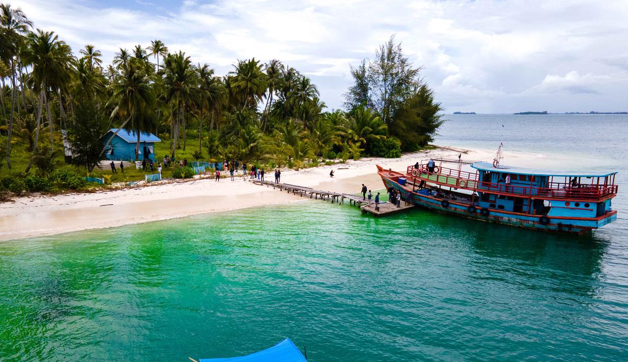 Keindahan pulau ini didukung oleh pepohonan kelapa dan pemandangan laut biru kehijauan yang memukau. Tampak foto udara memperlihatkan perahu nelayan di Pulau Panjang, yang pernah menjadi objek sengketa batas pulau antara Aceh dan Sumatra Utara, di Singkil, Provinsi Aceh bagian selatan, pada Rabu 12 November 2025. (CHAIDEER MAHYUDDIN/AFP)