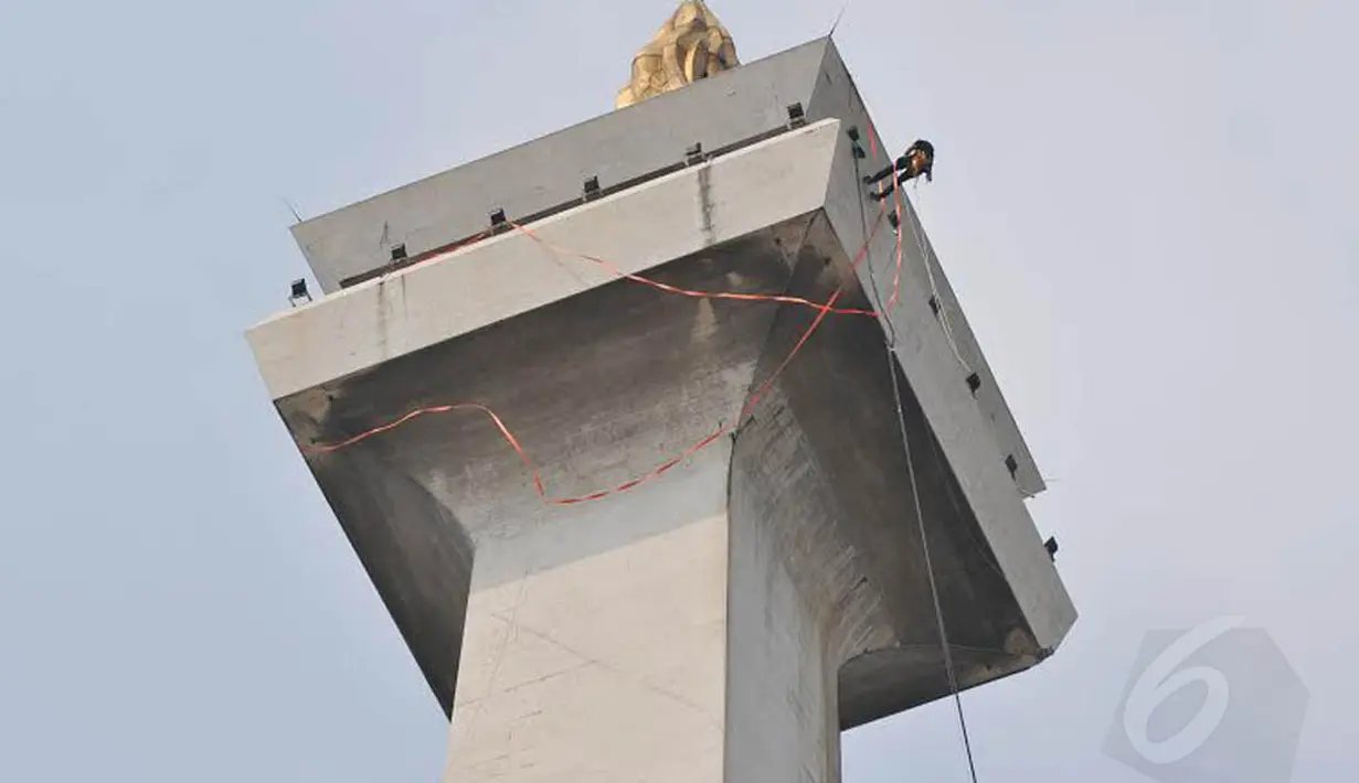 Monas mulai 'dimandikan' pada Kamis (08/05/14). Dengan terikat tali, seorang teknisi tampak membersihkan bagian atas tugu setinggi 132 meter (Liputan6.com/Johan Tallo)  