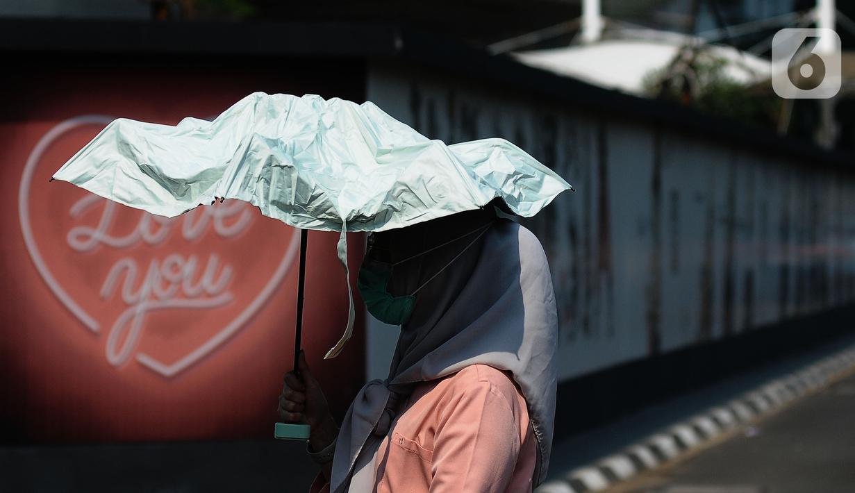 Pejalan kaki mengenakan payung untuk menghindari panas matahari di kawasan Kuningan, Jakarta, Selasa (26/9/2023). (merdeka.com/Imam Buhori)