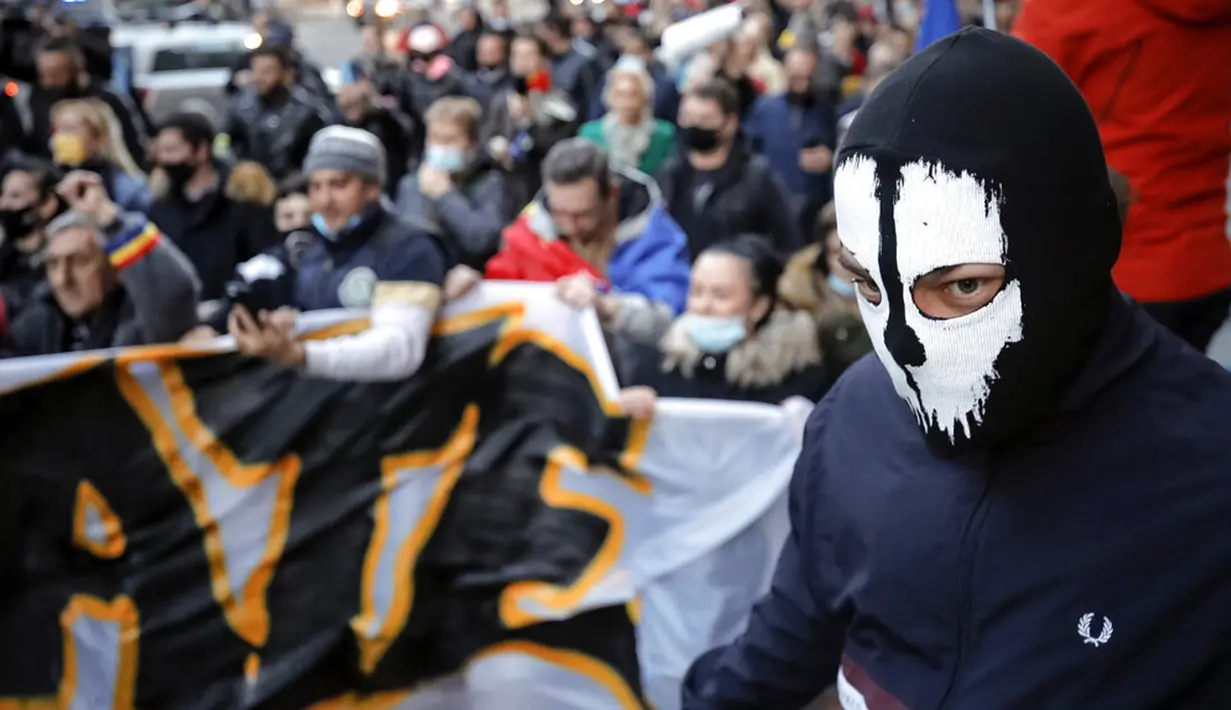 Warga yang memprotes pembatasan terkait pandemi COVID-19 berbaris di pusat Kota Bucharest, Rumania, Senin (29/3/2021). Ribuan pengunjuk rasa antipembatasan turun ke jalan di beberapa kota Rumania sehari setelah langkah pembatasan baru diberlakukan. (AP Photo/Vadim Ghirda)