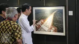 Presiden Joko Widodo melihat karya foto yang dipajang pada pameran foto jurnalistik Setahun Kerja Jokowi-JK di Museum Bank Mandiri, Jakarta, Jumat (18/12). Foto tersebut merupakan karya para anggota Pewarta Foto Indonesia (Liputan6.com/Faizal Fanani)