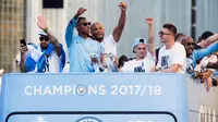 Kapten Manchester City, Vincent Kompany (tengah) bersama rekan setimnya melambaikan tangan dari atas bus beratap terbuka saat melakukan parade merayakan keberhasilan menjadi juara Liga Primer Inggris di Manchester, Senin (14/5). (Anthony Devlin/PA via AP)