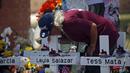 Seorang pria mencium salib Layla Salazar dalam sebuah peringatan di luar Robb Elementary School untuk menghormati para korban yang tewas dalam penembakan di sekolah awal pekan ini, Uvalde, Texas, Amerika Serikat, 28 Mei 2022. (AP Photo/Dario Lopez-Mills)