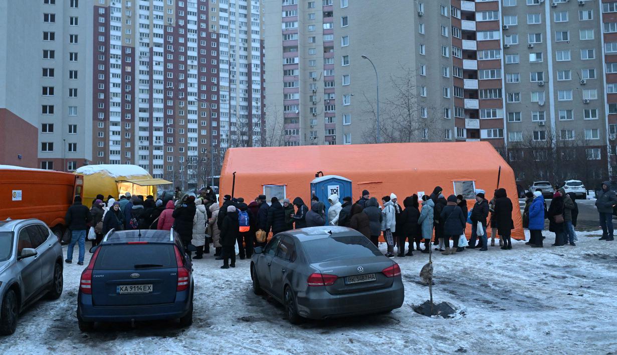 Bantuan makanan ini sangat penting untuk membantu mereka bertahan di tengah kondisi cuaca ekstrem dan krisis energi. Tampak dalam foto, warga setempat mengantre untuk menerima makanan hangat yang dibagikan oleh sukarelawan dari badan amal makanan yang berbasis di Amerika Serikat (AS), World Central Kitchen, membagikan makanan hangat kepada warga setempat di sebuah kawasan perumahan di Kyiv yang mengalami pemadaman listrik dan air akibat serangan Rusia yang menghantam sektor energi, Kamis 22 Januari 2026. (Sergei GAPON/AFP)