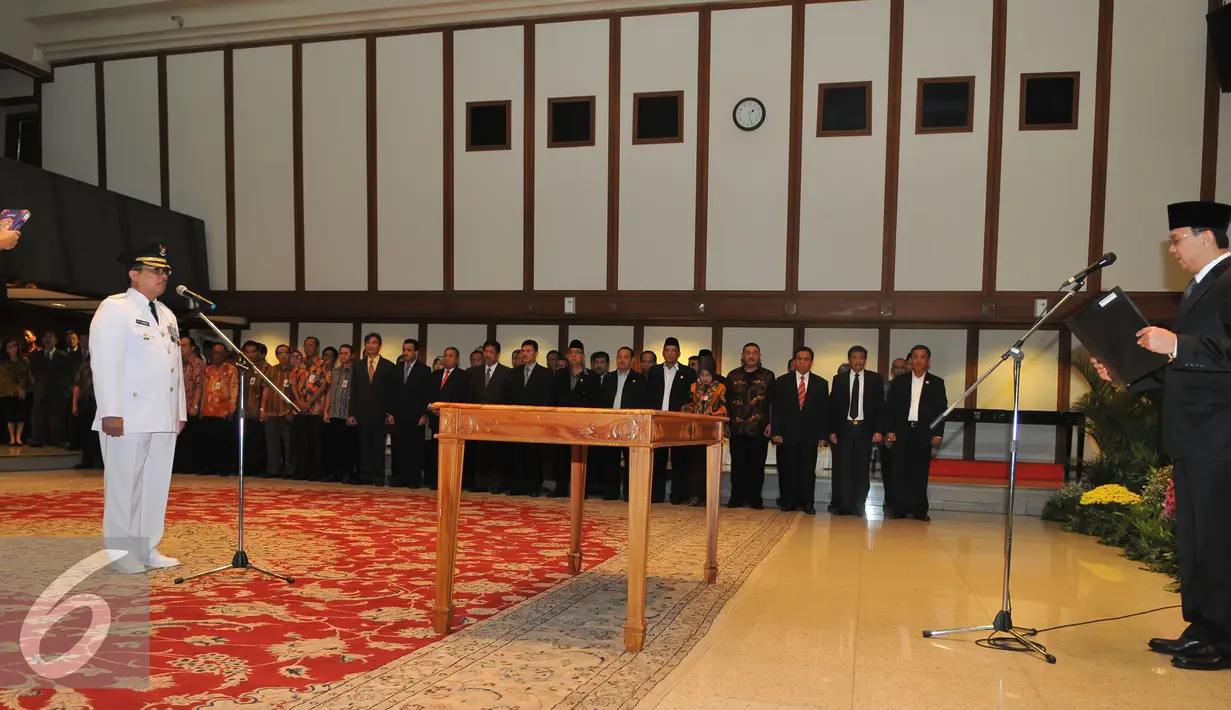 Basuki T Purnama (kanan ) membacakan sumpah ke calon Walikota Jaksel Tri Kurniadi pada saat pelantikan di balai kota, Jakarta, Kamis (13/8/2015). Tri resmi menggantikan Syamsuddin Noor yang dipecat. (Liputan6.com/Herman Zakharia)