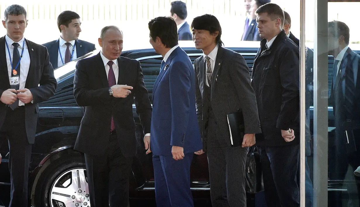 Presiden Rusia Vladimir Putin (Kedua Kiri) disambut oleh Perdana Menteri Jepang Shinzo Abe (tengah) setibanya kediaman Abe di Tokyo, Jepang, Jumat (16/12). Jepang dan Rusia rencananya akan membahas soal sengketa wilayah. (REUTERS / Frank Robichon)