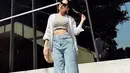 Gaya kasual yang minimalis namun menawan ala Azizah Salsha. Ia memadukan cropped top bermotif garis, ditumpuknya dengan kemeja putih dengan kancing dibuka, dan celana jeans panjang. [Foto: Instagram/azizahsalsha_]