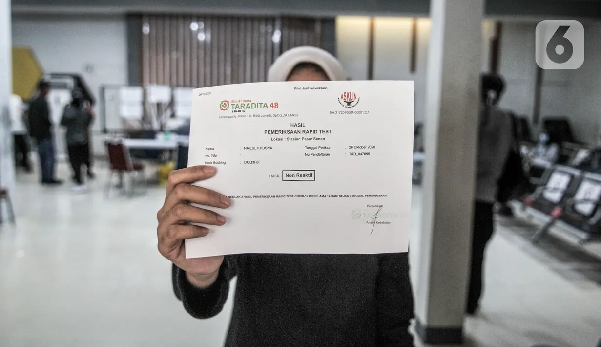 Calon penumpang menunjukkan hasil rapid test COVID-19 di Stasiun Pasar Senen, Jakarta, Senin (26/10/2020). Jumlah penumpang kereta jarak jauh mengalami lonjakan sehingga terjadi antrean panjang rapid test yang menjadi syarat wajib pengguna jasa KAI. (merdeka.com/Iqbal S. Nugroho)
