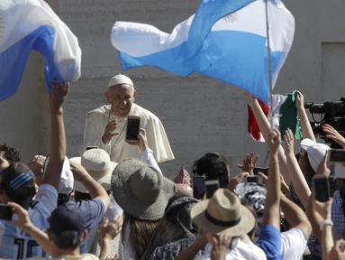 Fans mengibarkan bendera Argentina saat Paus Fransiskus melakukan pertemuan mingguan di Vatican, (27/6/2018). Perayaan tersebut tak lepas dari keeforia kemenangan Argentina atas Nigeria di Piala Dunia 2018. (AP/Alessandra Tarantino)