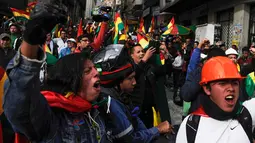 Orang-orang mengibarkan bendera Bolivia merayakan pengunduran diri Presiden Evo Morales di La Paz, Minggu (10/11/2019). Morales memutuskan mengundurkan diri buntut aksi protes yang dilatarbelakangi dugaan dirinya melakukan kecurangan dalam pemilu dalam beberapa pekan terakhir. (JORGE BERNAL/AFP)