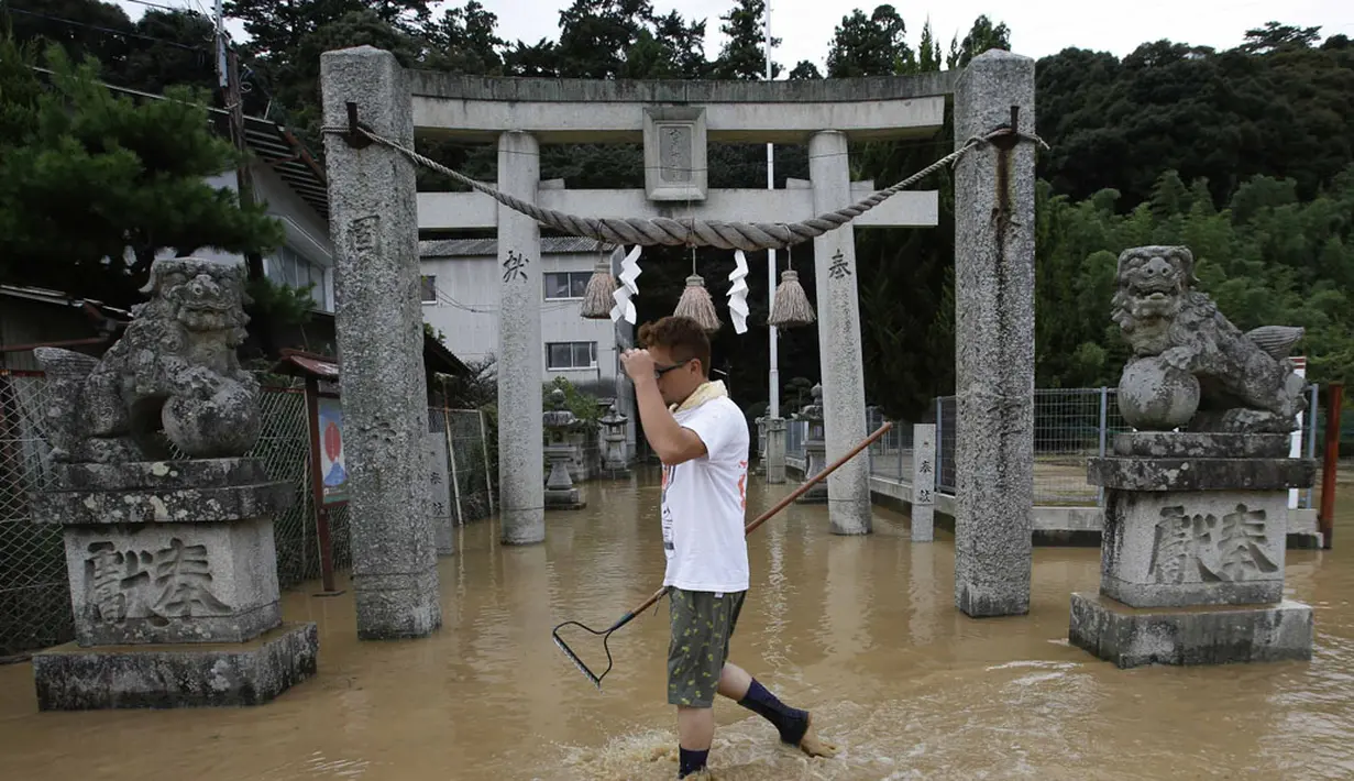 Salah satu warga melintas di depan gerbang sebuah kuil yang ikut terendam akibat bencana tanah longsor di wilayah perumahan di Asaminami, Hiroshima, Jepang, (20/8/2014). (REUTERS/Toru Hanai)