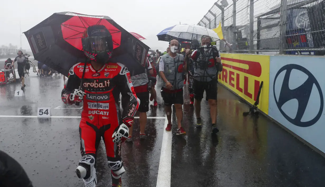 Tim mekanik dan kru kembali ke paddock saat hujan deras sebelum Race 1 World Superbike (WSBK) di Pertamina Mandalika International Street Circuit, Lombok Tengah, Nusa Tenggara Barat, Sabtu (20/11/2021). Hujan deras memaksa Race 1 WSBK Mandalika ditunda pada 21 November. (AP Photo/Achmad Ibrahim)
