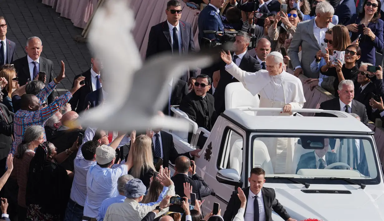 Seekor burung terbang melintas saat Paus Leo XIV menggunakan popemobile berkeliling Lapangan Santo Petrus Basilika di Vatikan, Minggu 18 Mei 2025. (Jacquelyn Martin/POOL/AFP)