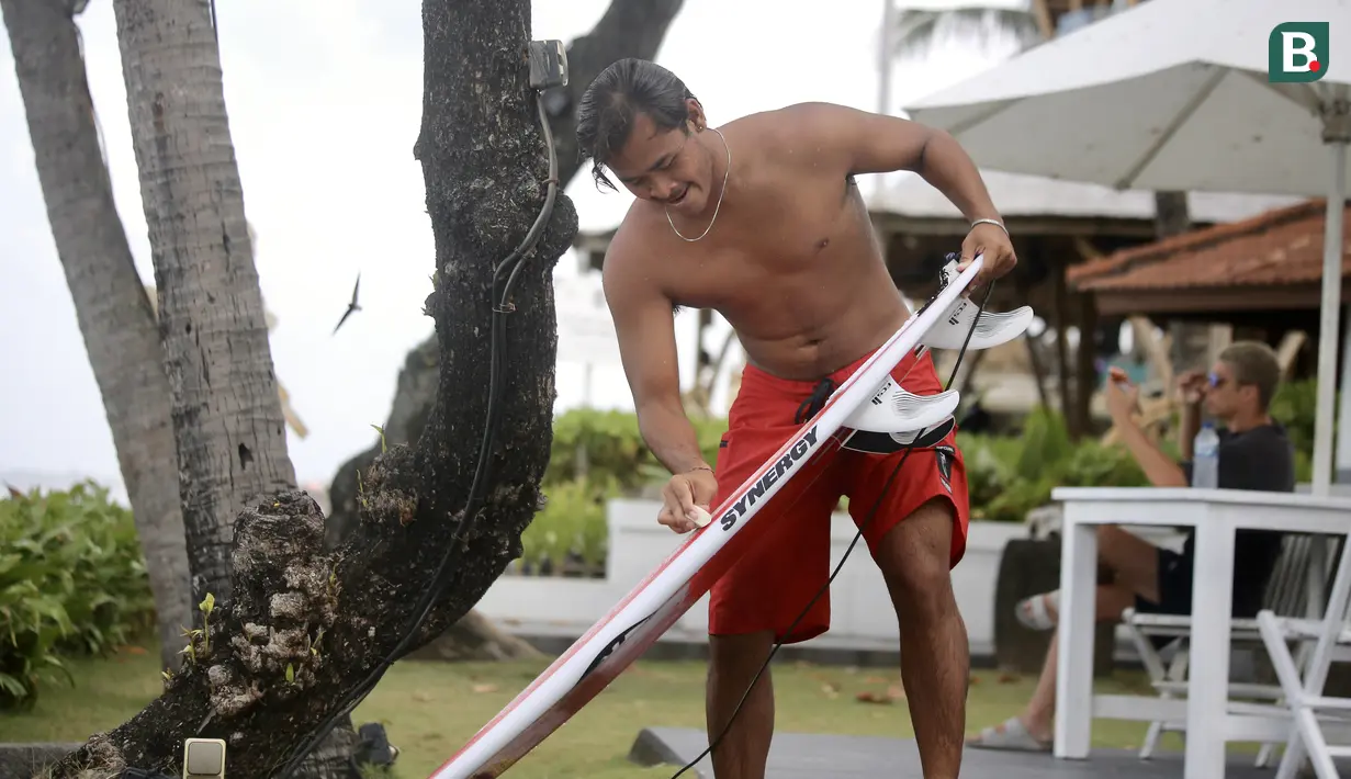 Atlet Timnas Surfing Indonesia, I Made Pajar Ariana, mengoleskan wax pada papan selancarnya sebelum menjalani sesi latihan di Pantai Berawa, Kuta Utara, Selasa (15/9/2026). Persiapan tersebut dilakukan sebagai bagian dari pematangan fisik dan teknik Pajar sebelum tampil pada Asian Games 2026 di Aichi-Nagoya, Jepang. (Bola.com/Alit Binawan)
