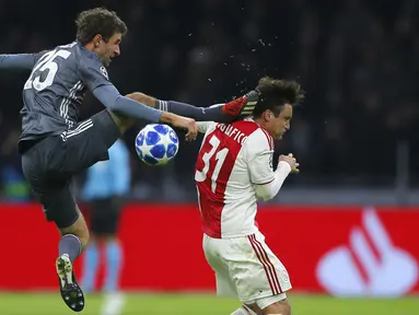 Gelandang Bayern Munchen, Thomas Mueller, menendang kepala bek Ajax Amsterdam, Nicolas Tagliafico, pada laga Liga Champions di Johan Cruyff Arena, Amsterdam, Rabu (12/12). Kedua tim bermain imbang 3-3. (AP/Peter Dejong)