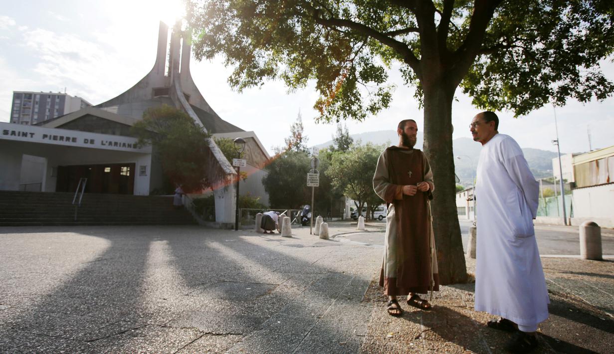 Pastor dan imam Muslim berbincang di depan gereja Saint-Pierre-de-l’Ariane di Nice, Prancis, Minggu (31/7). Muslim di penjuru Prancis menghadiri misa sebagai solidaritas atas pembunuhan seorang pastor oleh militan Islam. (Jean Christophe MAGNENET/AFP)