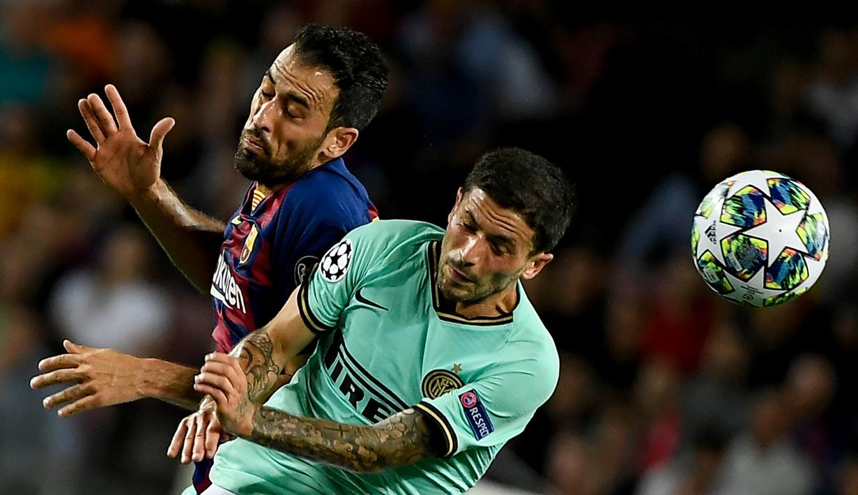 Gelandang Barcelona, Sergio Busquets, duel udara dengan gelandang Inter Milan, Stefano Sensi, pada laga Liga Champions di Stadion Camp Nou, Barcelona, Rabu (2/10). Barcelona menang 2-1 atas Inter. (AFP/Lluis Gene)