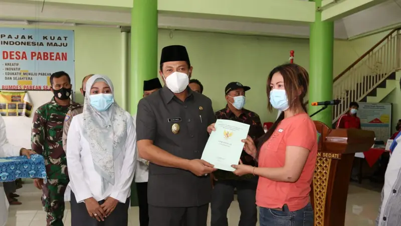 Wakil Bupati (Wabup) Sidoarjo Subandi menyerahkan sertifikat tanah kepada warga Desa Pabean Sedati. (Dian Kurniawan/Liputan6.com)