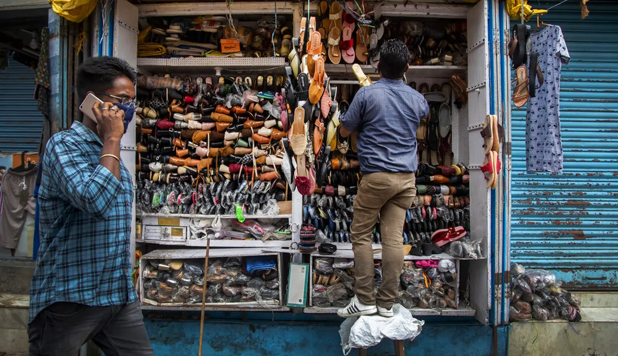 Seorang penjaga toko menata sepatu di Gauhati, India, Rabu (9/6/2021). India melonggarkan sebagian pembatasan untuk mengekang penyebaran virus corona COVID-19. (AP Photo/Anupam Nath)