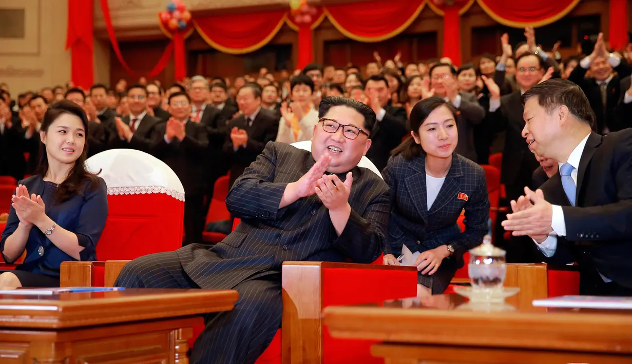 Pemimpin Korea Utara Kim Jong-Un didampingi istrinya Ri Sol Ju (kanan) bertepuk tangan saat menonton penampilan kelompok seni dari China di Pyongyang, Korea Utara (17/4). (Korean Central News Agency/Korea News Service via AP)