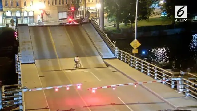 Seorang pesepeda wanita melewati papan peringatan di Racine Street Bridge, Wisconson, AS. Alhasil ia terjatuh di celah jembatan otomatis tersebut.