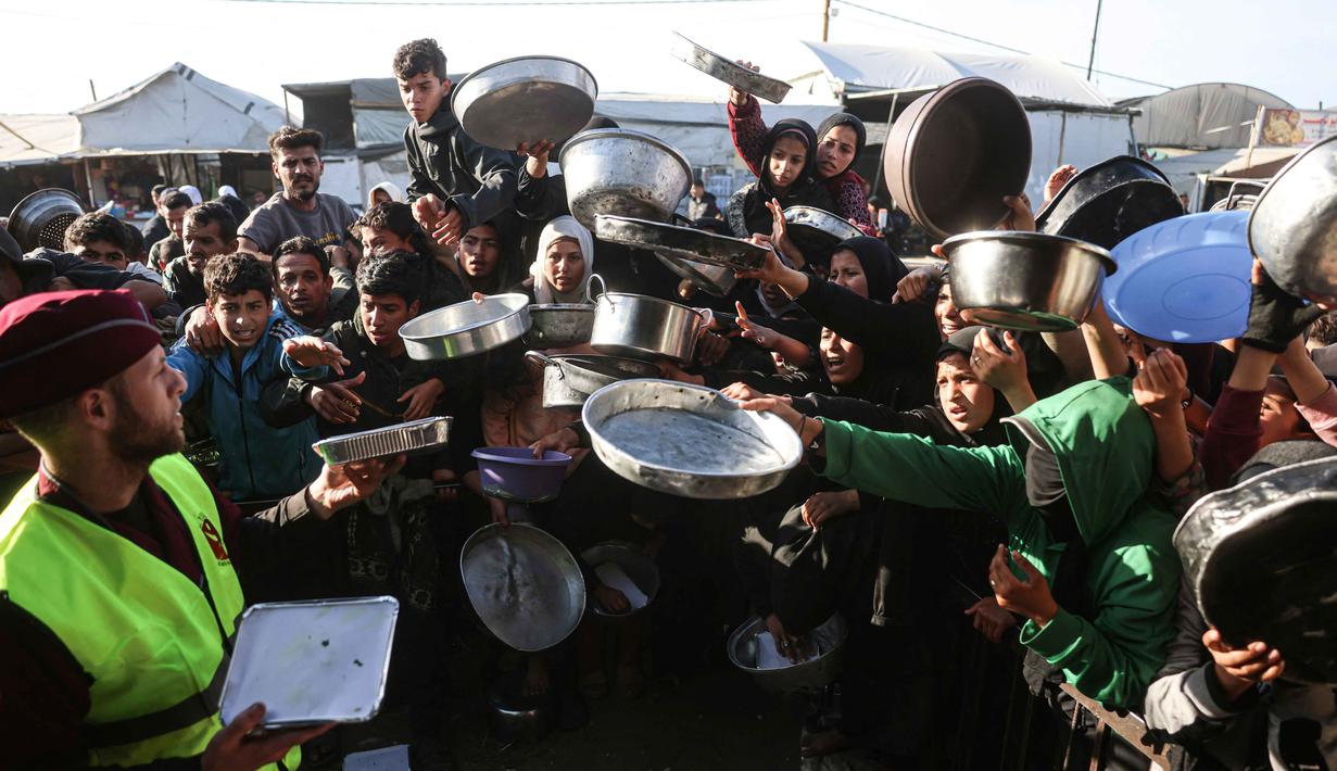 Lonjakan harga pangan yang drastis dan mengancam jutaan warga dengan bencana kelaparan yang berulang. Tampak dalam foto, warga Palestina yang mengungsi berebut untuk makanan di Khan Younis, selatan Jalur Gaza pada Jumat 6 Maret 2026. (Bashar Taleb/AFP)