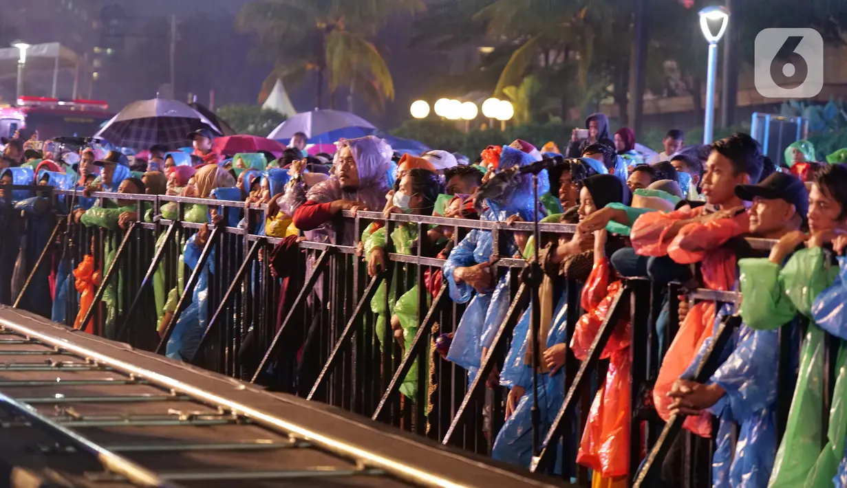 Sejumlah warga menyaksikan Rhoma Irama selama konser Happy New Year 2020 di Bundaran HI, Jakarta, Selasa (31/12/2019). Raja Dangdut Rhoma Irama dan Soneta Group menjadi band utama yang mengiringi musik legendarisnya di konser tersebut. (Liputan6.com/Herman Zakharia)