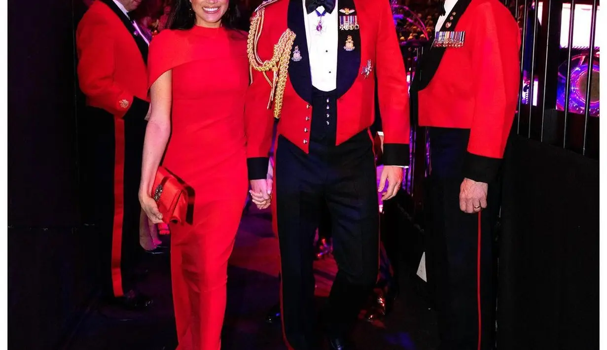 Gaun merah yang mencuri perhatian membalut tubuh Meghan Markle. Detail cape di bagian atas bahu dan clutch bernuansa senada menyempurnakan penampilan Meghan Markle di sini. [Foto: Instagram/sussexroyal]