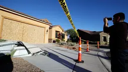 Seorang pria mengambil gambar rumah pelaku penembakan Las Vegas, Stephen Paddock (64), di Mesquite, Nevada, Senin (2/10). Rumah yang didominasi warna cokelat itu dilengkapi satu garasi dan tanpa memiliki pagar di sekitarnya. (AP Photo/Chris Carlson)